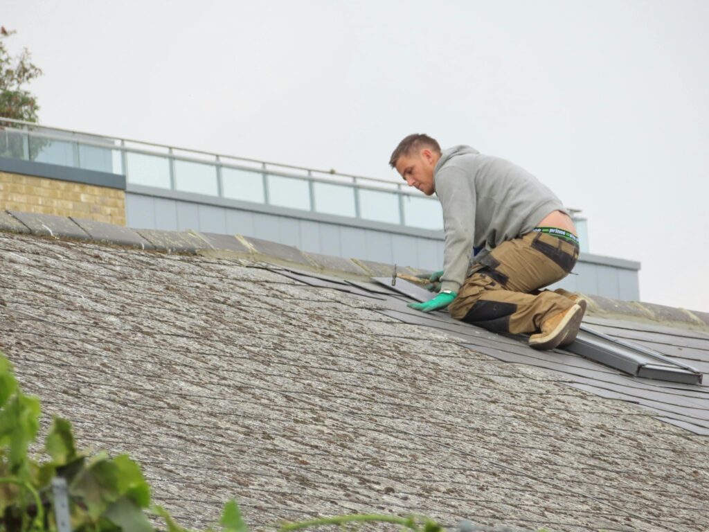 Contractor installing asphalt shingles on a residential roof.