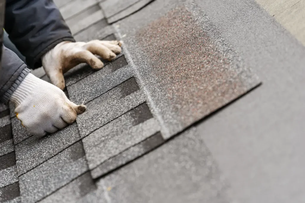 Roofer installing asphalt shingles on a residential house.