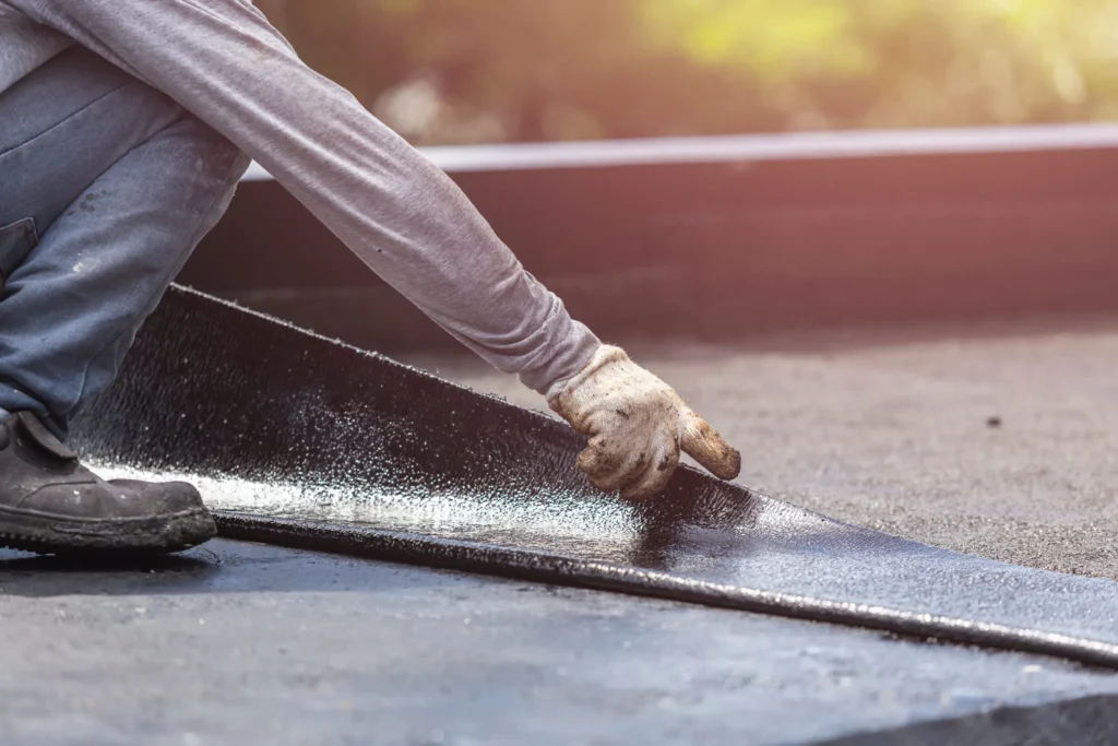 A roofing professional carefully installing a new layer of roofing material to extend the life of a residential roof.
