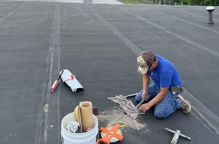 A professional roofing technician performing maintenance and sealing on a large commercial flat roof system to ensure long term durability.