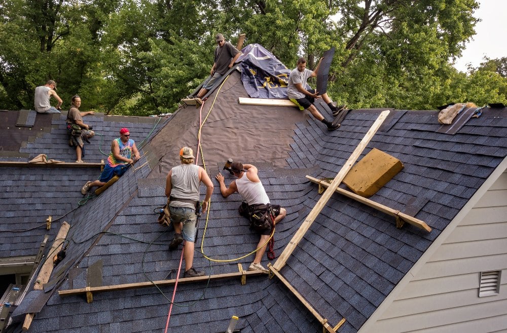 A professional roofing crew installing a brand new weather resistant roofing system on a residential house.